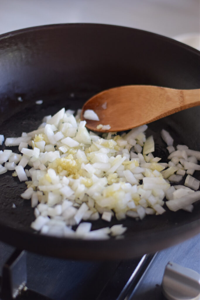 Adding diced onions to a skillet.