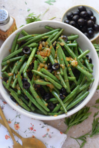 Sauteed green beans in a white bowl.