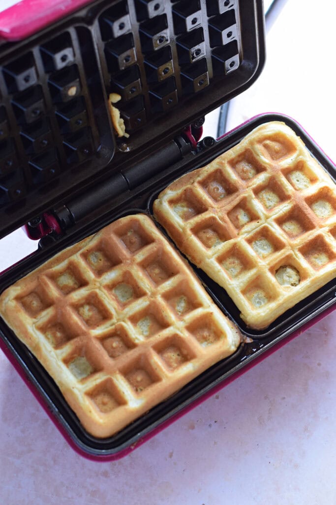 Golden waffles in a waffle maker.