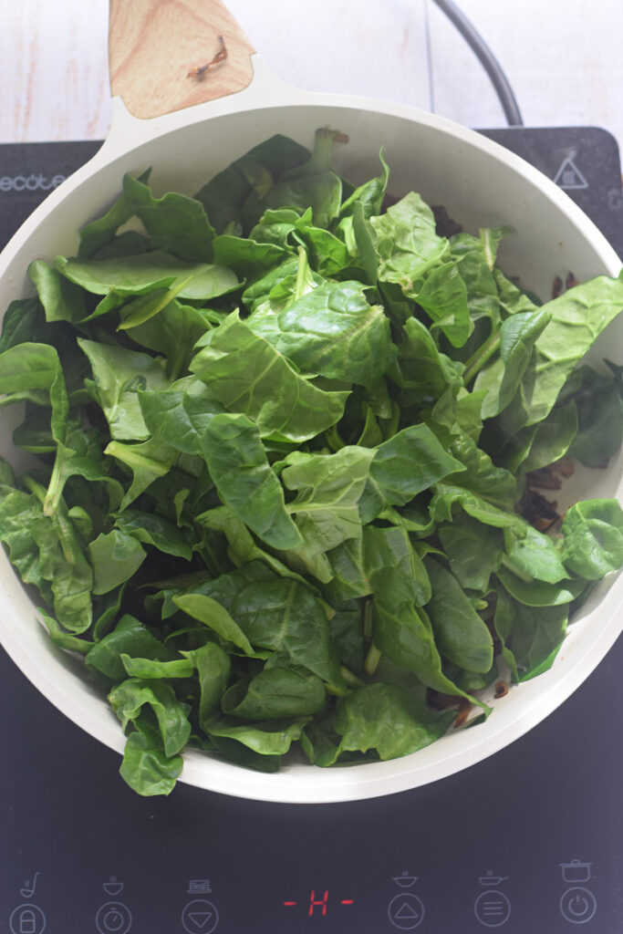 Adding spinach to a skillet.