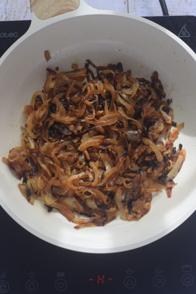 Caramelized onions in a white skillet.