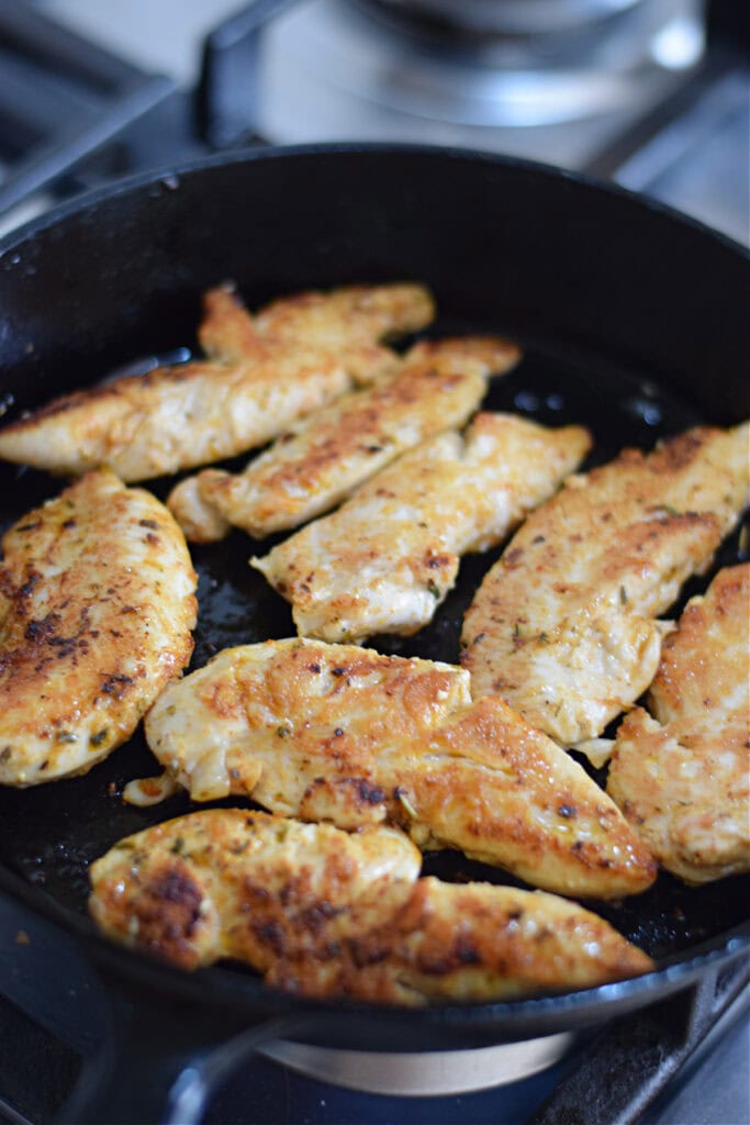 Cooking chicken tenders in a cast iron skillet.