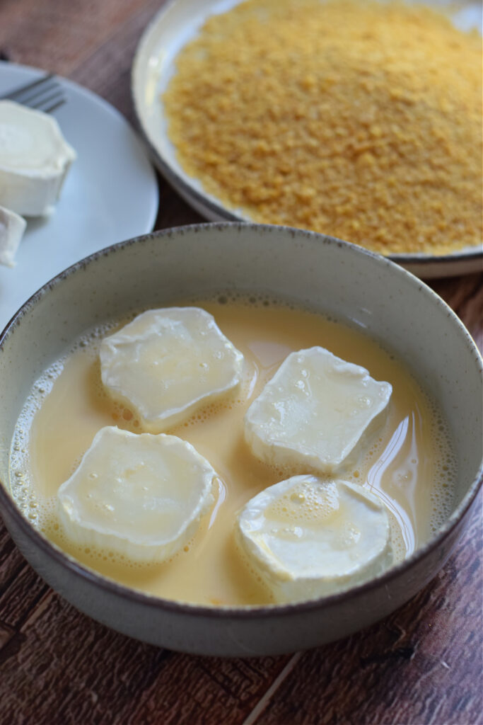 Coating cheese in whisked eggs.
