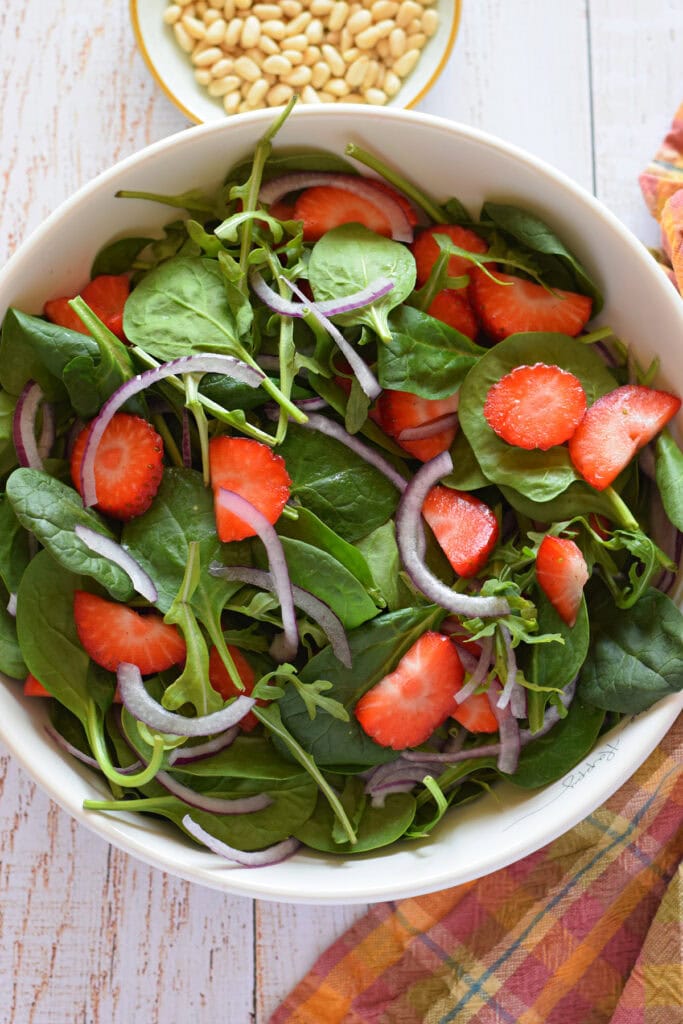 Strawberry spinach salad in a white bowl.