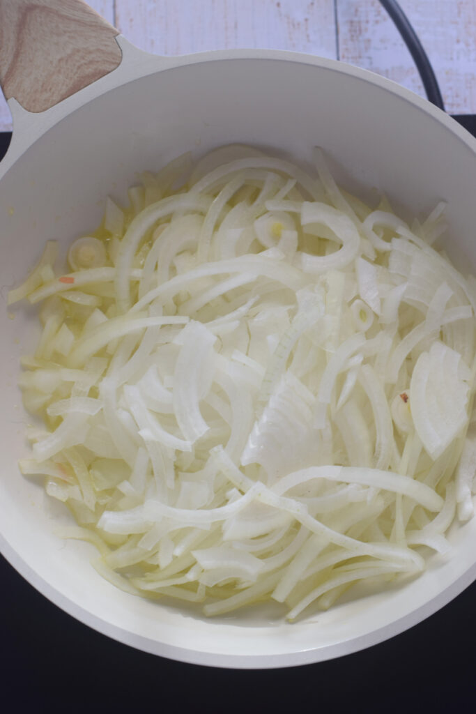 Adding onions to a skillet.