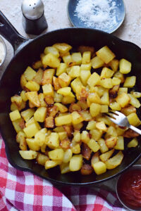 Fried cut potatoes in a skillet.