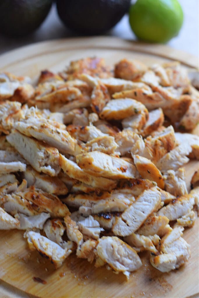Sliced up chicken on a wooden board.