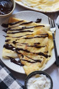 Chocolate dessert crepes on a white plate.