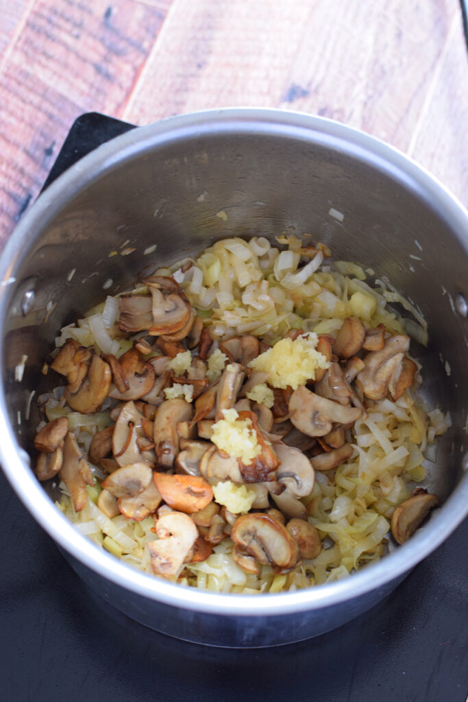 cooking mushrooms and leeks in a saucepan.