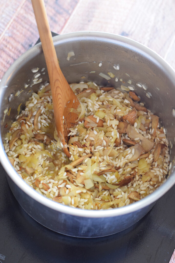 Adding white wine to risotto in a saucepan.