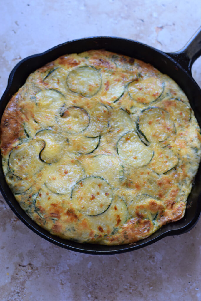 Zucchini and parmesan frittata in a cast iron skillet.