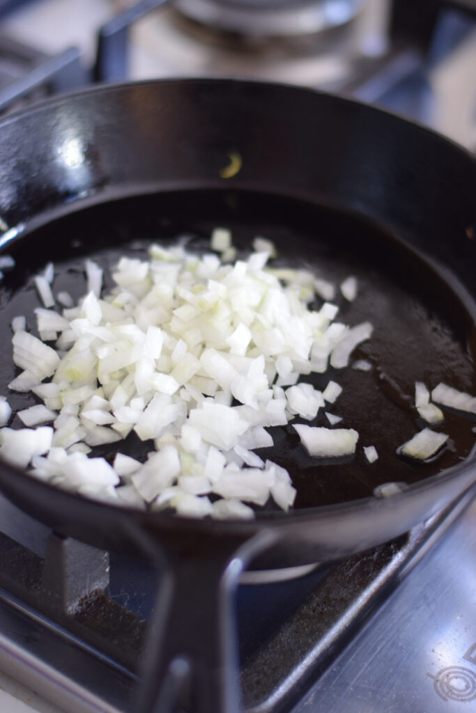 Adding onions to a skillet.