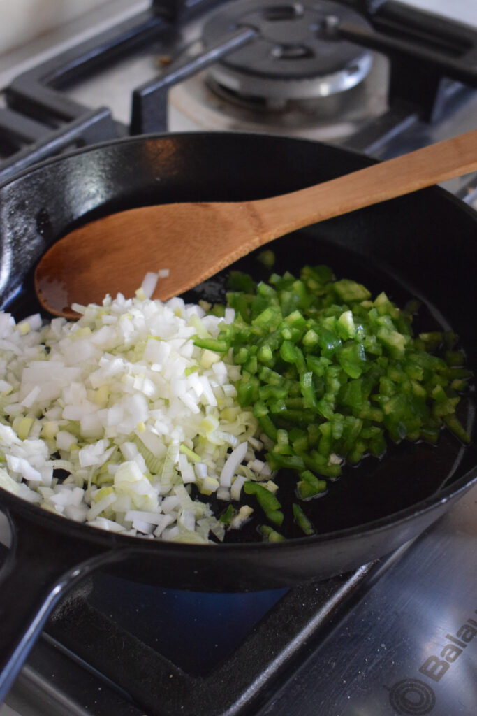 Cooking peppers and onions in a skillet.