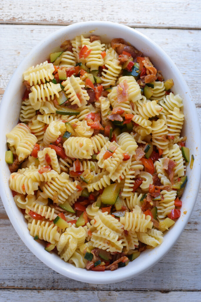 Making a pasta bake in a white dish.