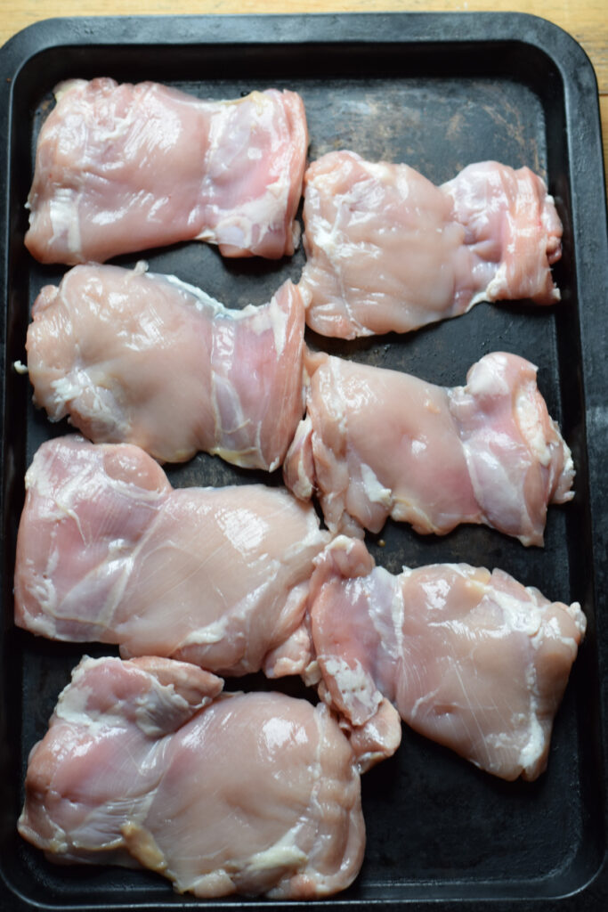 Chicken thighs on a baking tray.