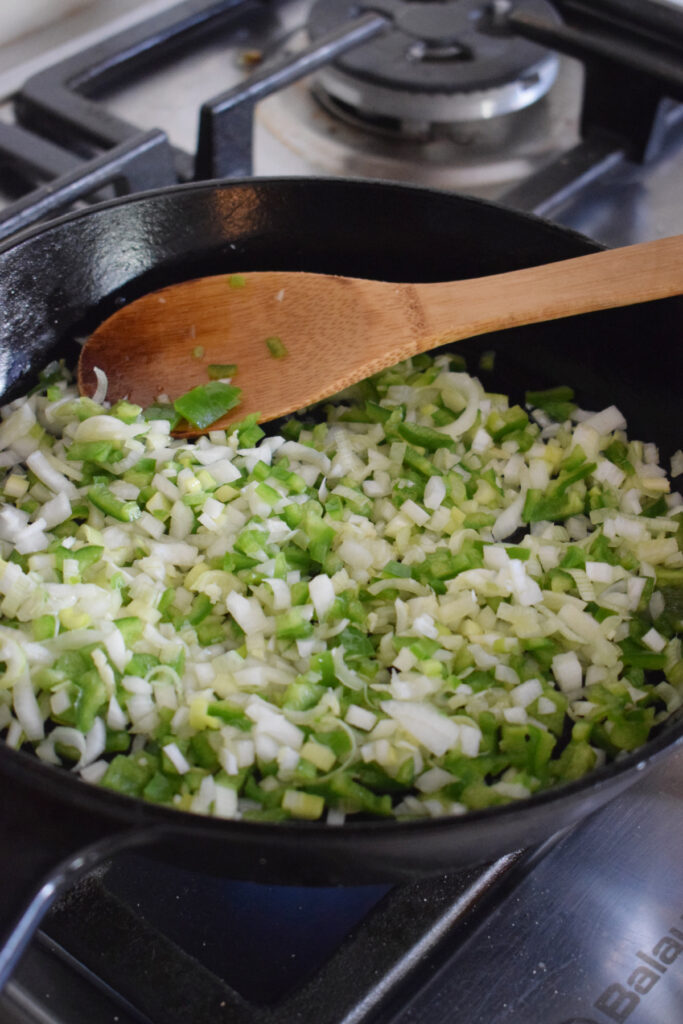 Cooking peppers and onions in a skillet.