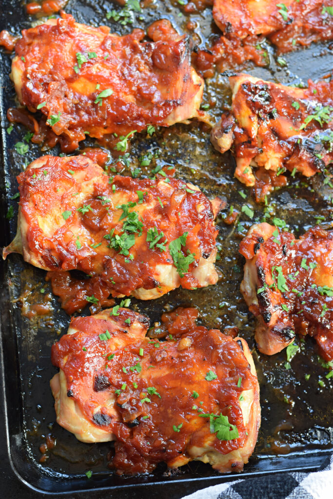 Close up of oven barbecue chicken thighs on a tray.