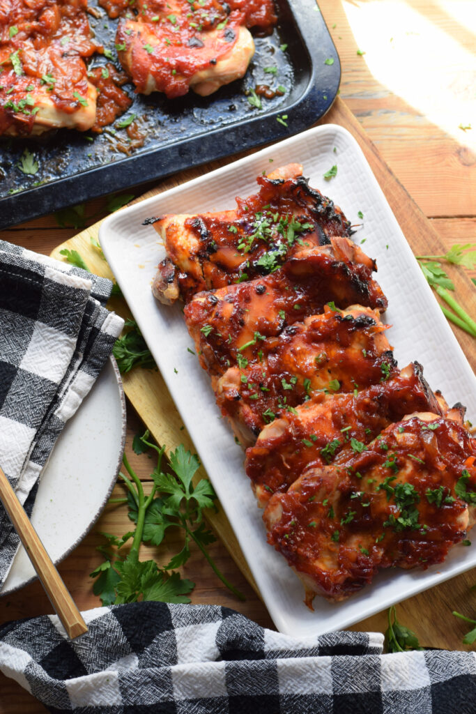 Barbecue chicken thighs on a white plate.