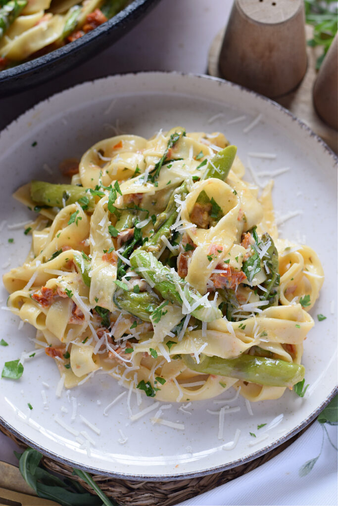 Close up of sun dried tomato tagliatelle on a white plate.