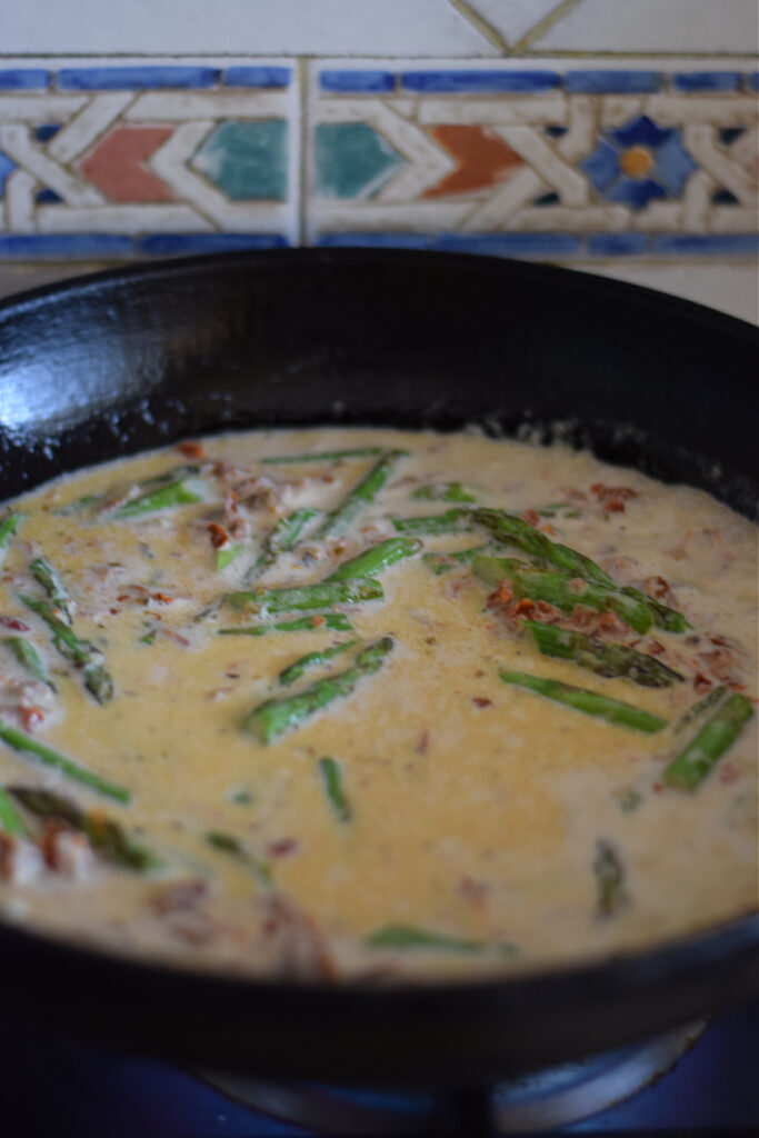Making a sun dried tomato pasta sauce in a skillet.