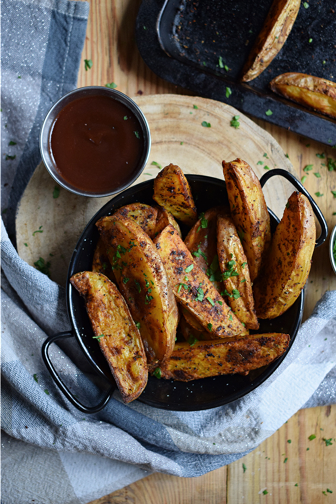 Paprika potatoes in a black bowl with a dipping sauce