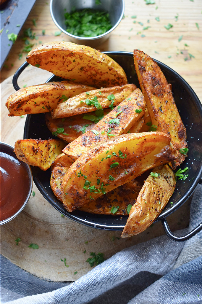 paprika spiced potato wedges in a black serving dish