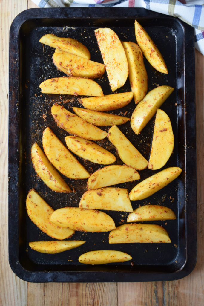 potatoes on a baking tray rubbed in a spice blend