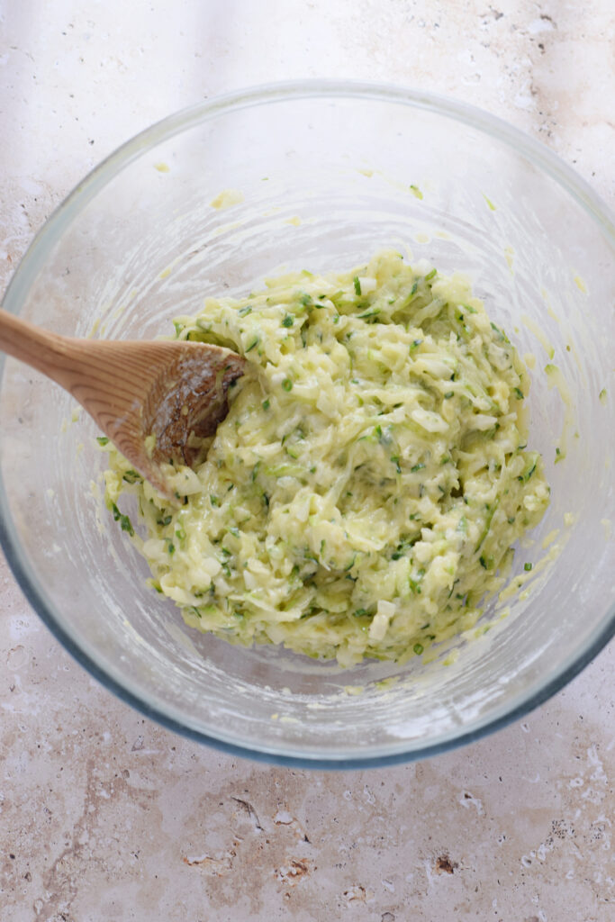 Zucchini fritter batter in a glass bowl.