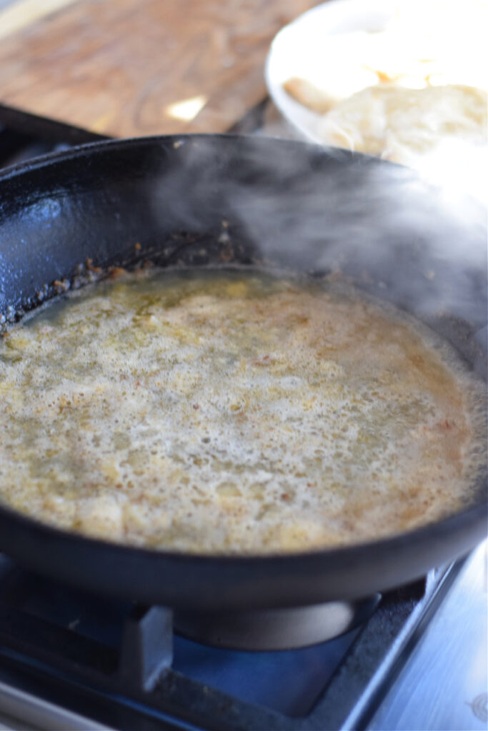 Adding broth to a skillet.