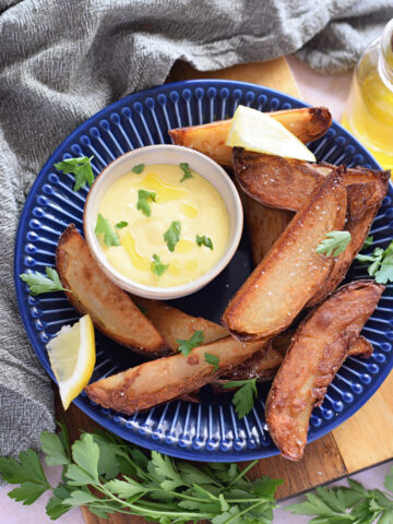 Garlic aioli dipping sauce in a small bowl with potato wedges.