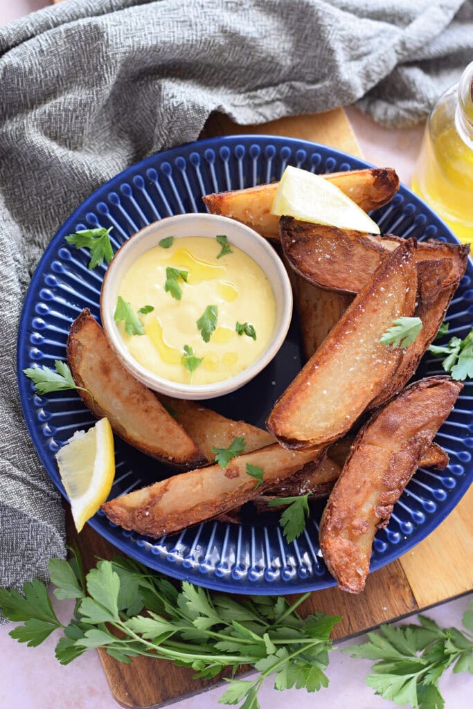 Garlic aioli dipping sauce in a small bowl with potato wedges.