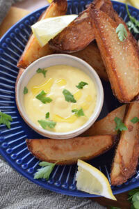 garlic aioli sauce with potato wedges on a blue plate.