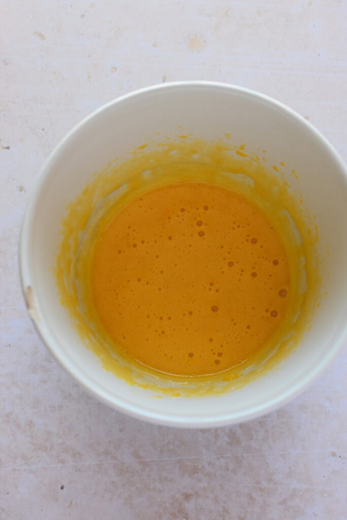 Whisked egg yolks in a bowl.