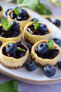 Blueberry cheesecakes on a white serving plate.