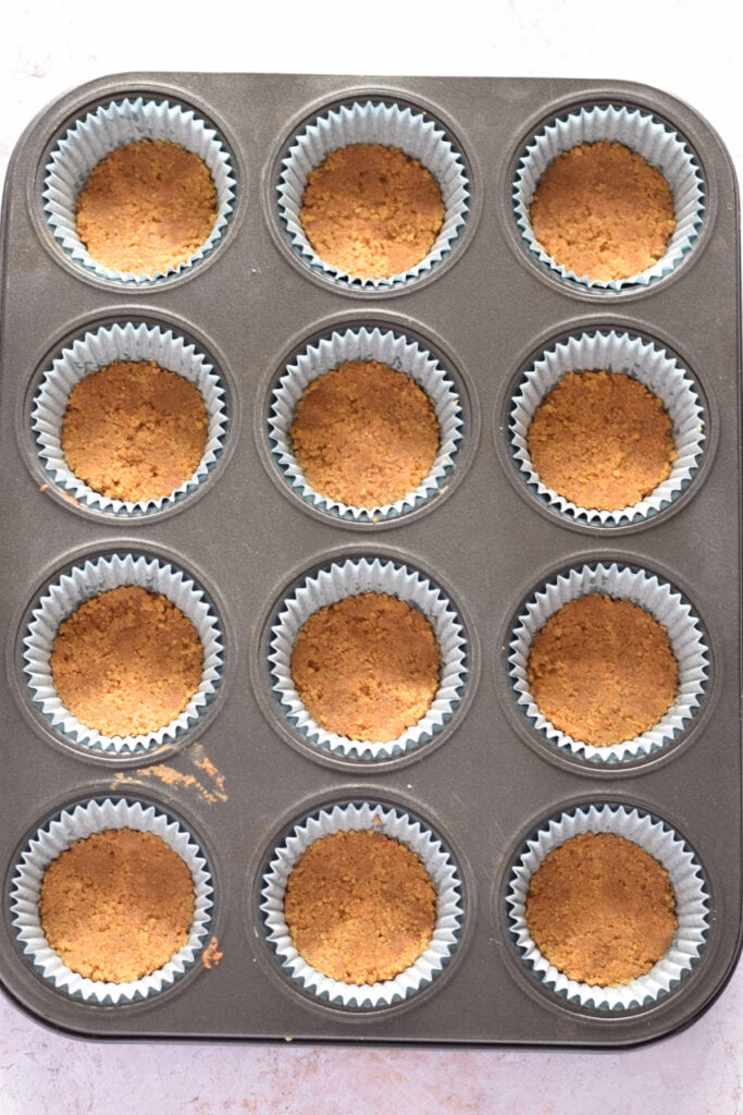 Mini cheesecake mini cups filled with cookie crumbs.