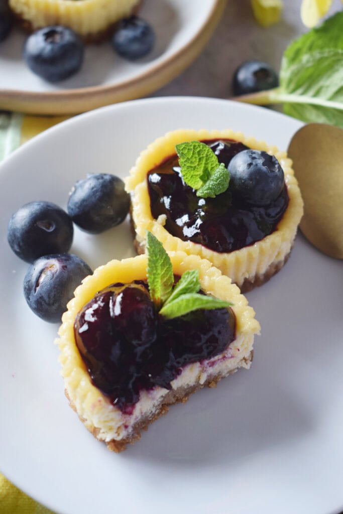Close up of mini blueberry cheesecakes on a white plate.