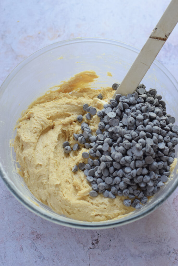 Adding chocolate chips to cookie dough.