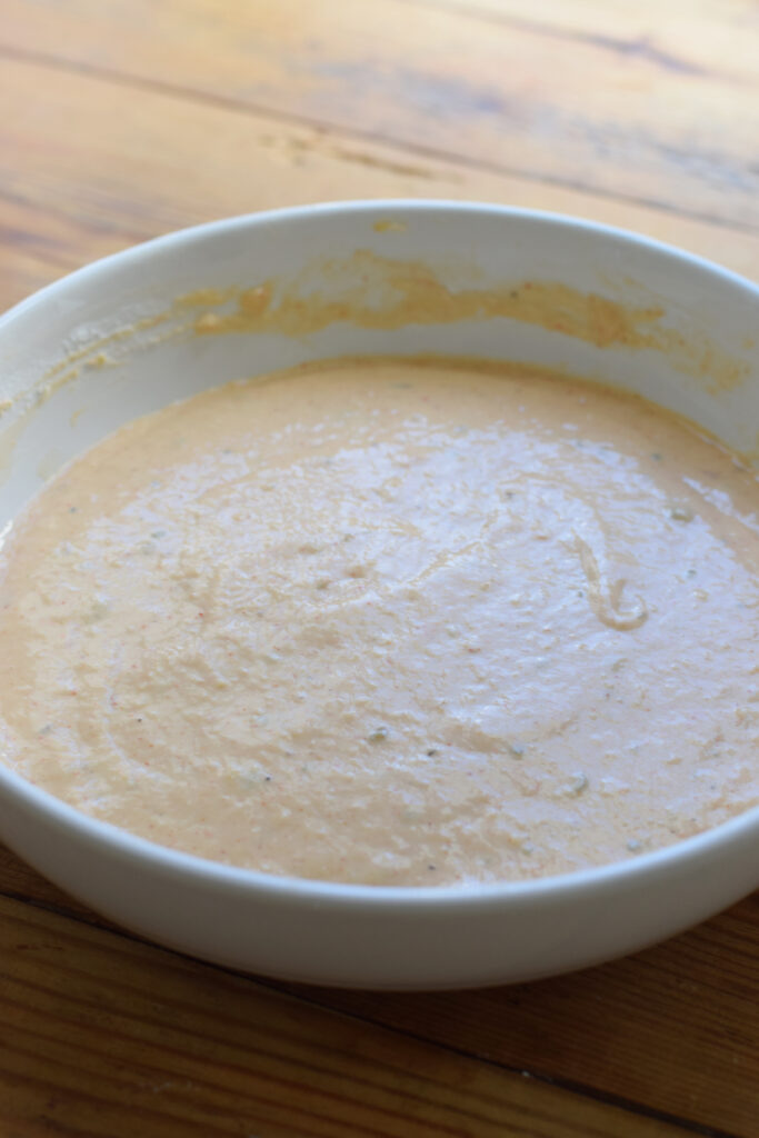 Whisked batter for onion rings in a bowl.