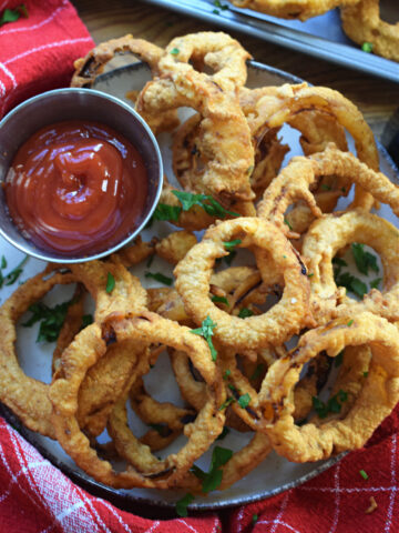 Crispy fried onion rings on a plate with a sauce.