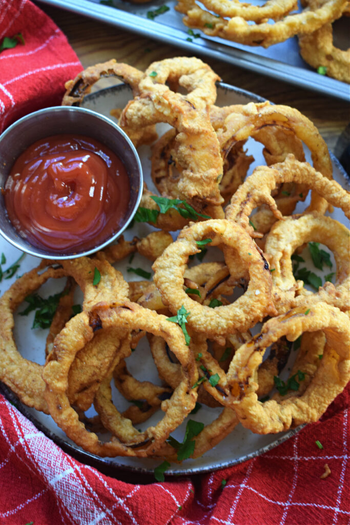 Crispy fried onion rings on a plate with a sauce.