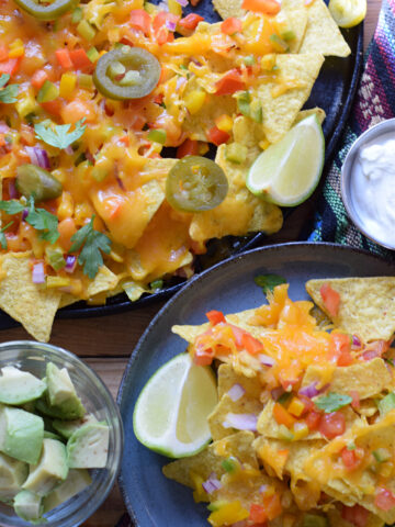 Loaded veggie nachos on a platter and a serving plate.