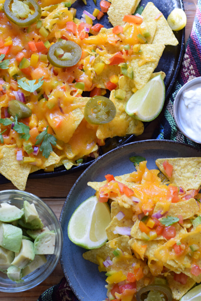 Loaded veggie nachos on a platter and a serving plate.