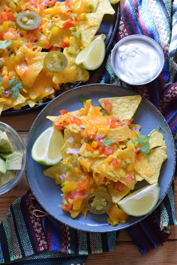 Vegetable nachos on a serving plate with sour cream on the side.