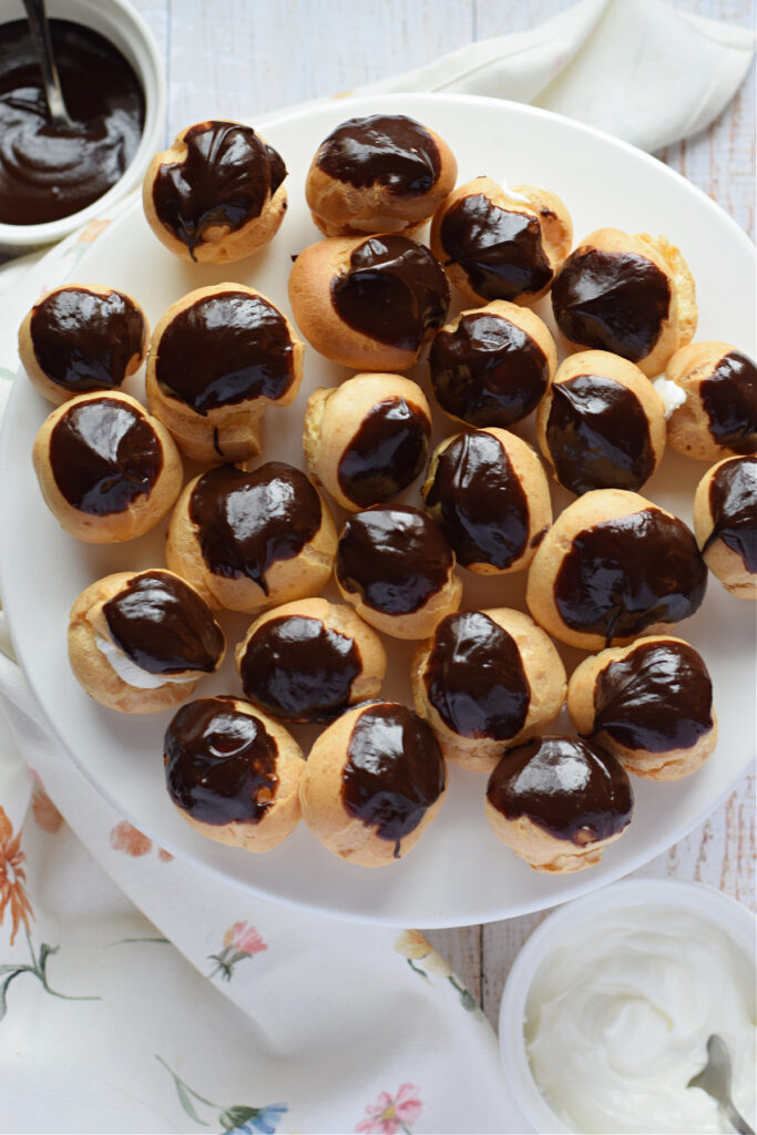Profiteroles with cream and chocolate on a white plate.