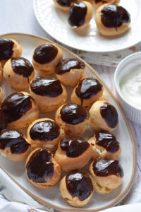Profiteroles with cream on a tray.