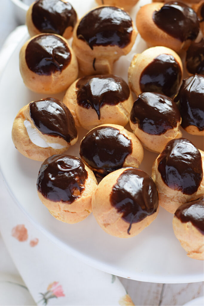 Close up of profiteroles on a white plate.