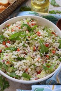 Close up of a rice and vegetable salad in a white bowl.