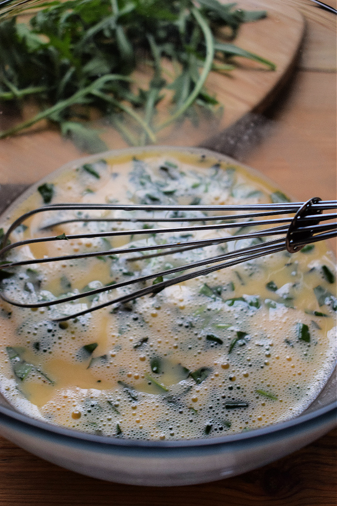 whisked eggs in a bowl with fresh basil