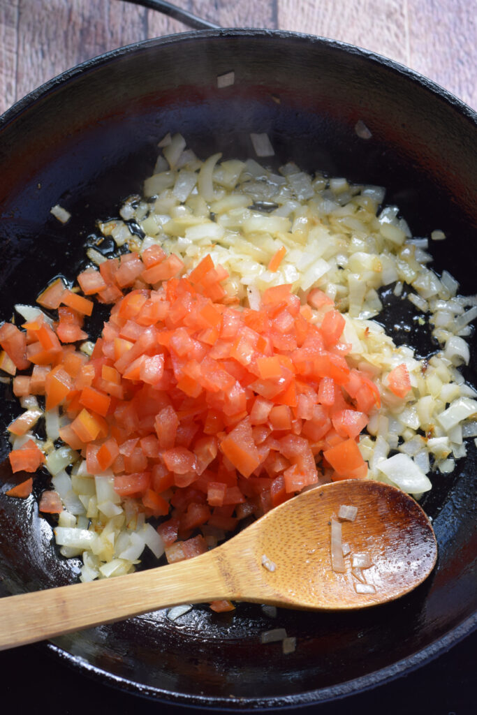 Cooking tomatoes in a skillet with onions.