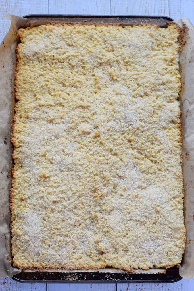 Baked coconut bars in a baking tray.